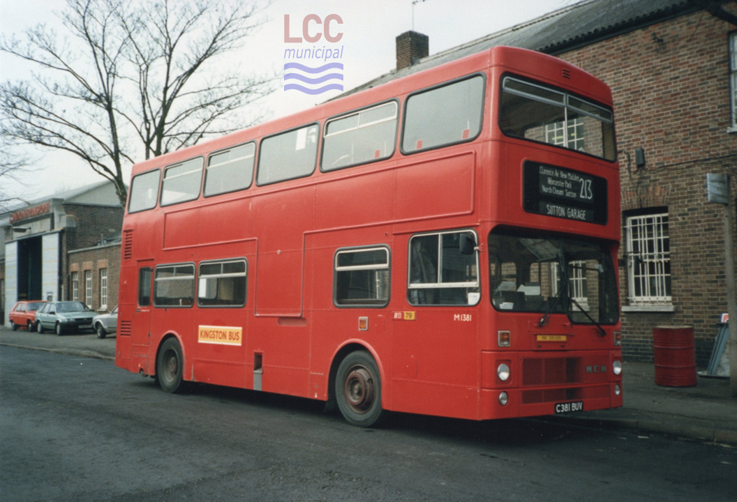 M1381 is a red double deck bus. It is seen outside Sutton Bus Garage, a low and long brick-built building. The garage allocation on the side of the bus is NB, which denotes the former Norbiton Garage.