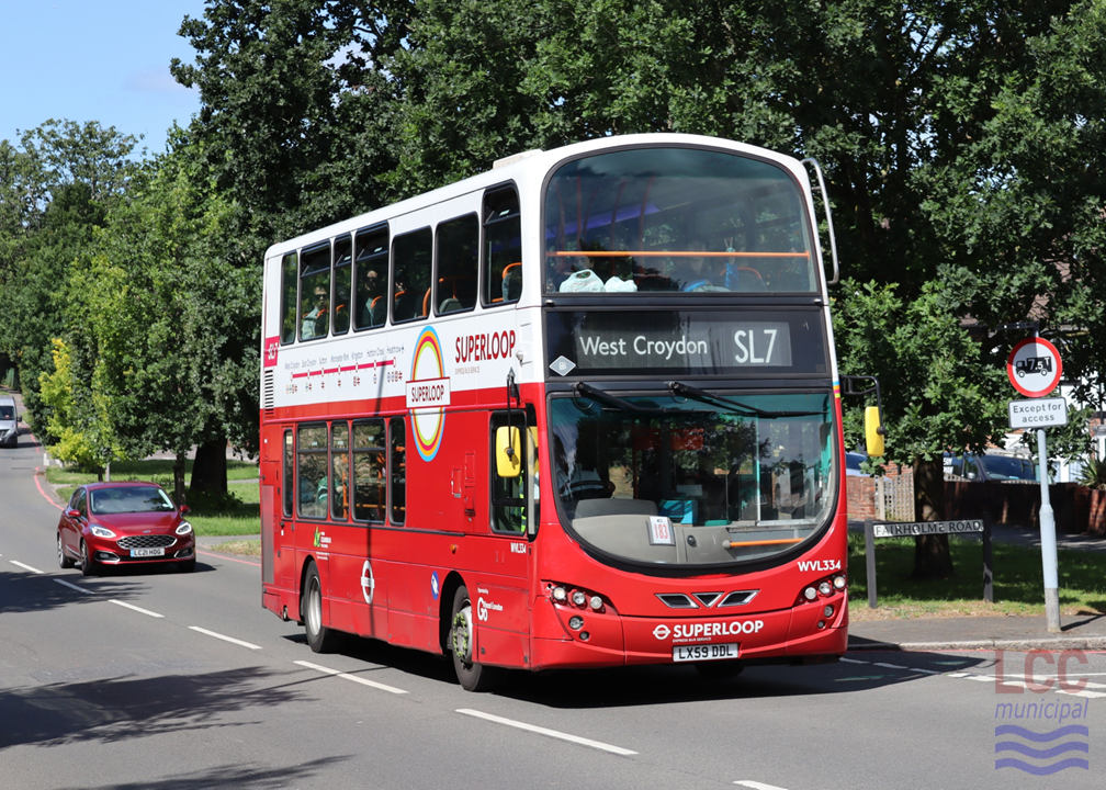 The bus is in Superloop branding, which sees the bottom half of the bus painted red and the upper part painted white. The route taken is clearly indicated along the side of the bus. The side also includes a large Superloop logo, which is a variant of the London Transport roundel. The bus is shown on a tree-lined suburban main road.