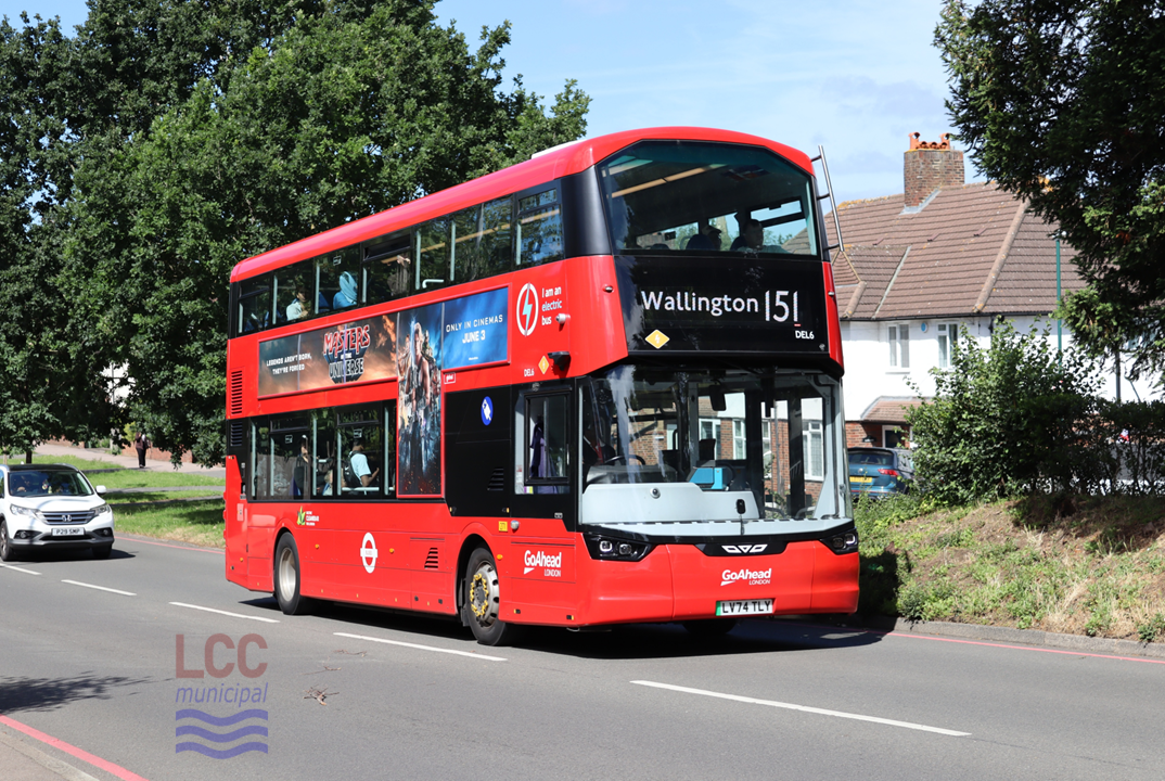 DEL6 is a red double-decker. One of its distinguishing features is the rather angled upper deck front window. The bus is on the 151 route to Wallington and is seen on a tree-lined suburban main road.