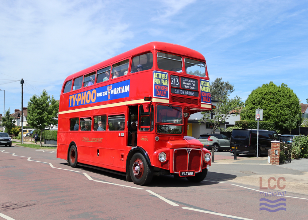 RM188, a red double deck front-engine rear-entrance bus. It is travelling toward the camera on a suburban street with houses and trees behind. The side of the bus carries a large advertisement saying "Typhoo puts the T in Britain"